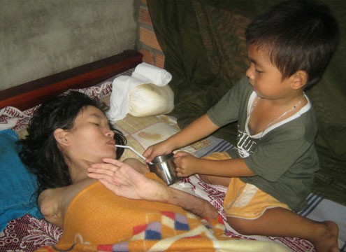 Sau buổi đến trường, bé Gia Huy trở về chăm sóc mẹ tàn phế. Ảnh: Nguyễn Ngọc